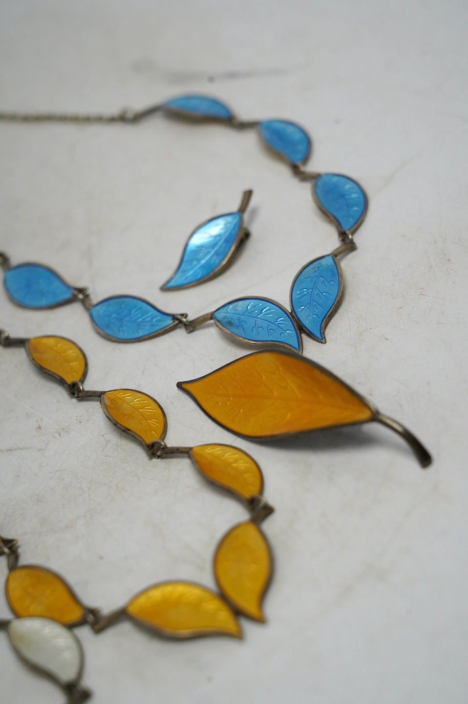 Seven items of David Andersen sterling and enamel jewellery, including necklace and pair of earrings in cream enamel, necklace and one earring in blue and a necklace and brooch in yellow, largest necklace 40cm. Condition